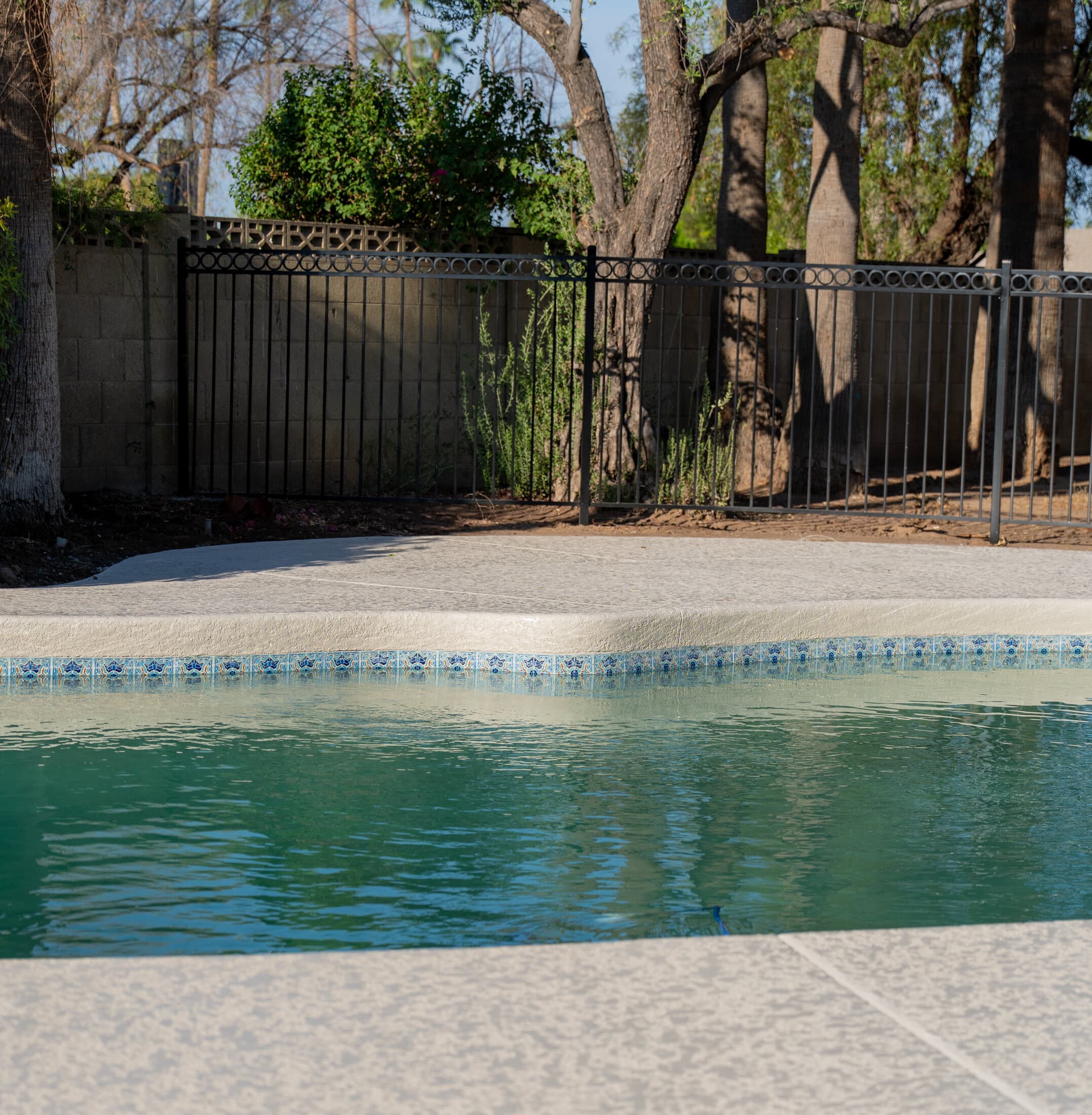 Resurfaced pool deck with decorative tile coping