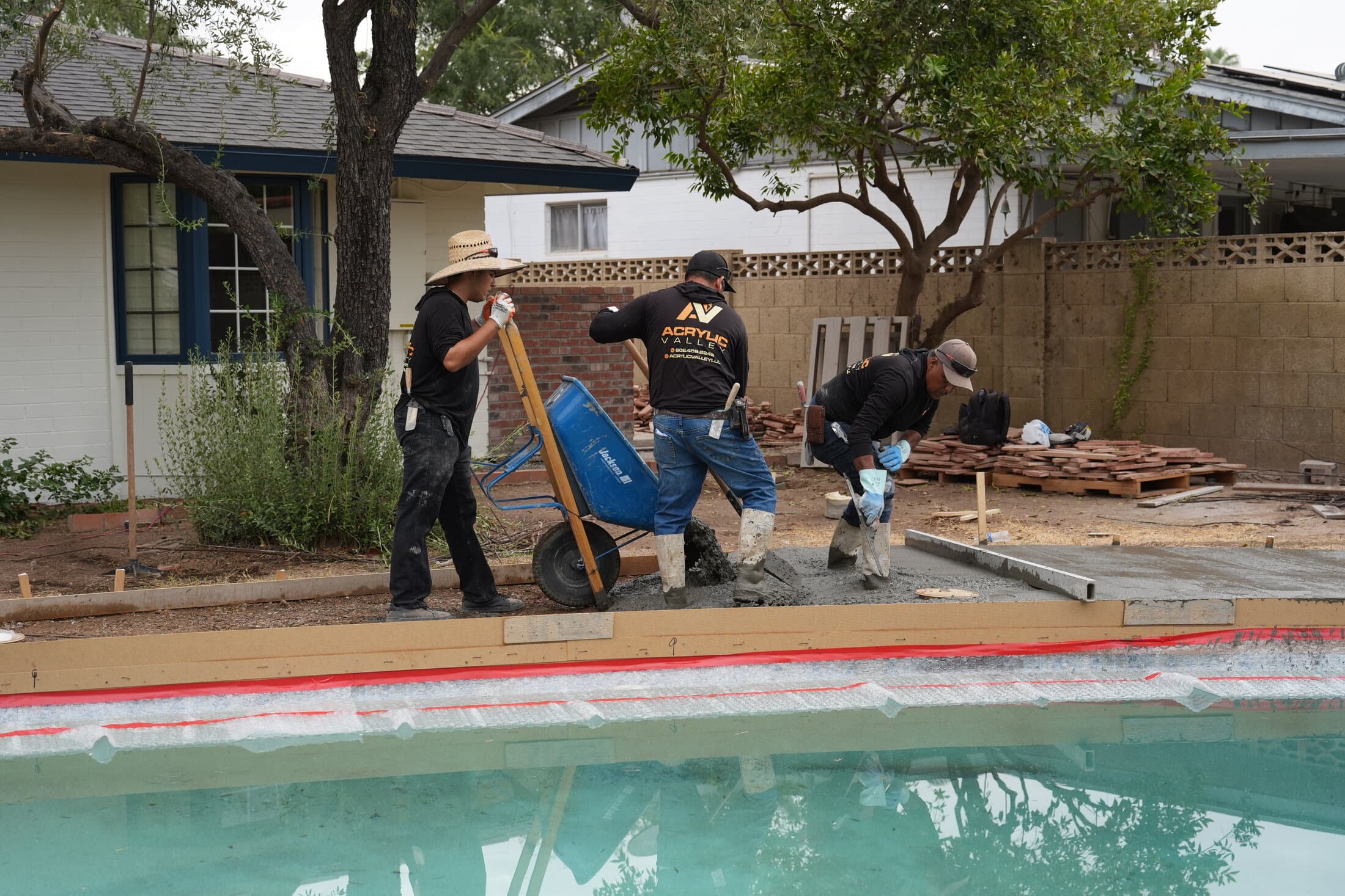 Acrylic Valley crew pouring concrete from a wheelbarrow
